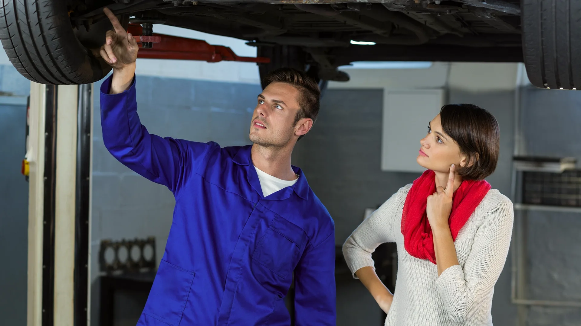 photo of a mechanic and car buyer inspecting a used car undercarriage