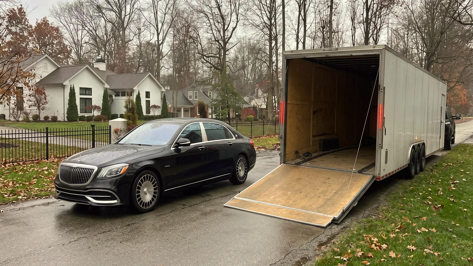 Luxury car next to an enclosed auto transport trailer