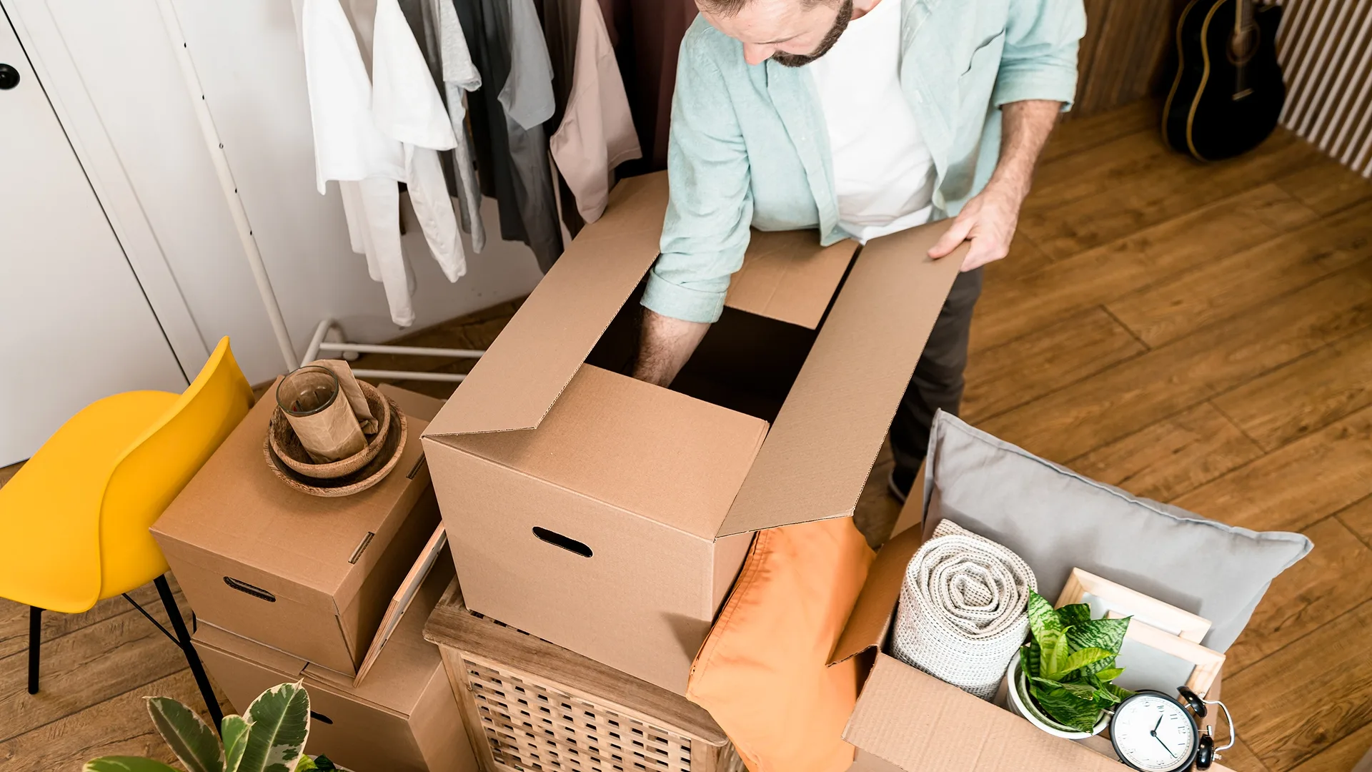 Man packing household belongings into moving boxes